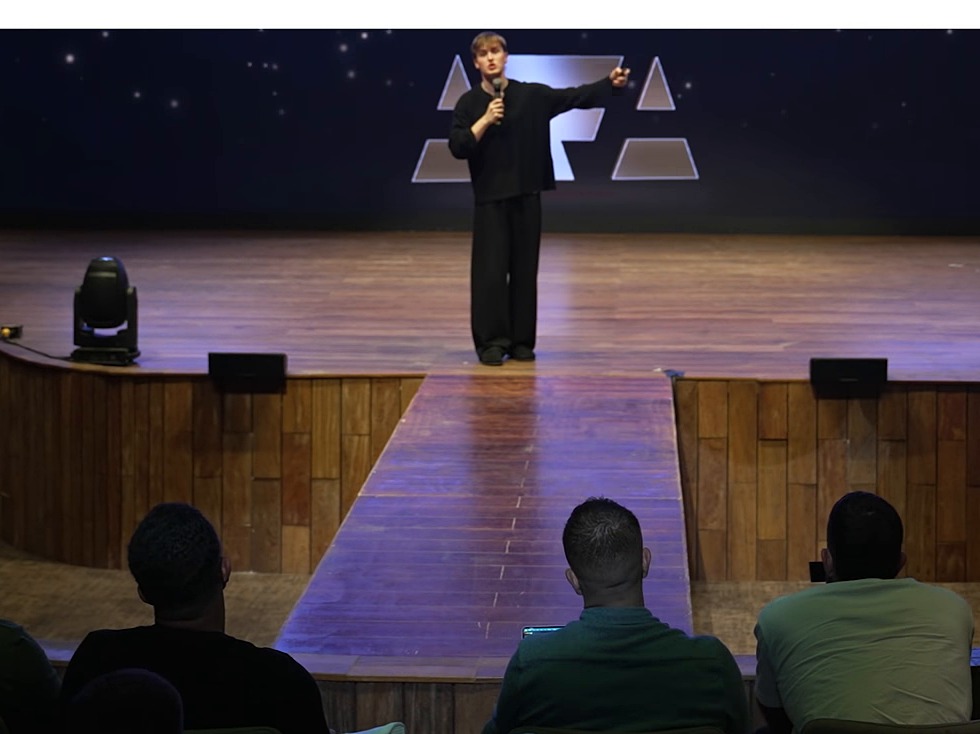 Jake Trinder presenting on stage with a microphone