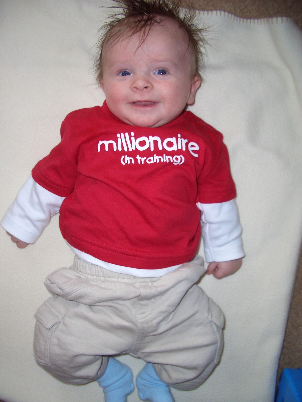Jake as a baby in a red sweatshirt that reads millionaire (in training)
