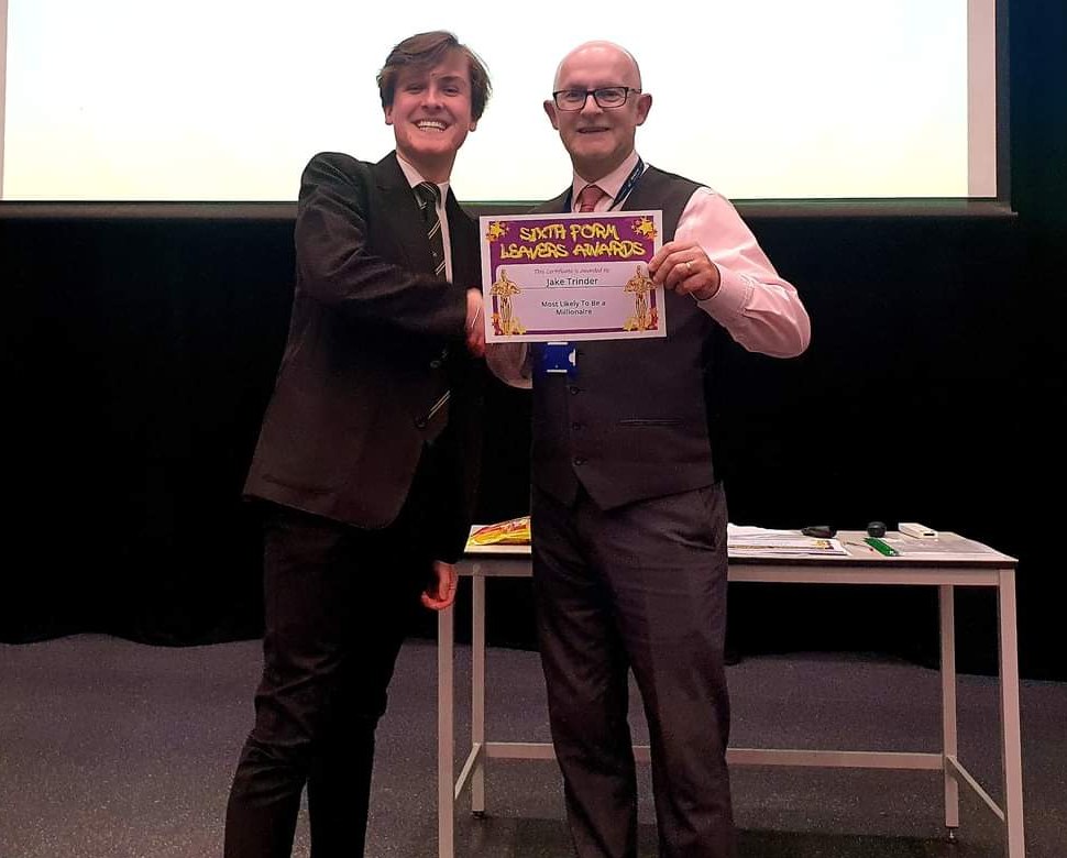 Jake in school uniform, smiling, shaking hands as he receives a Sixth Form Leavers Awards certificate that reads Most Likely To Be a Millionaire