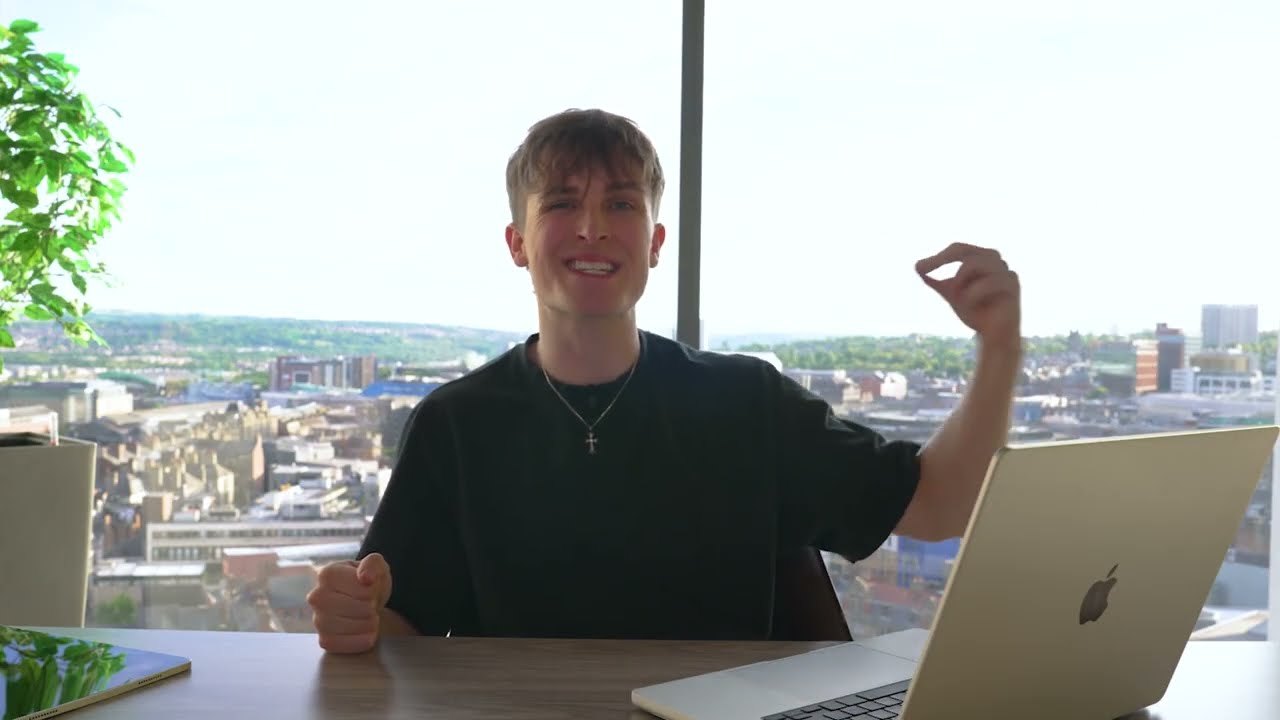 Jake Trinder at his desk with a laptop above the Newcastle skyline, talking to camera