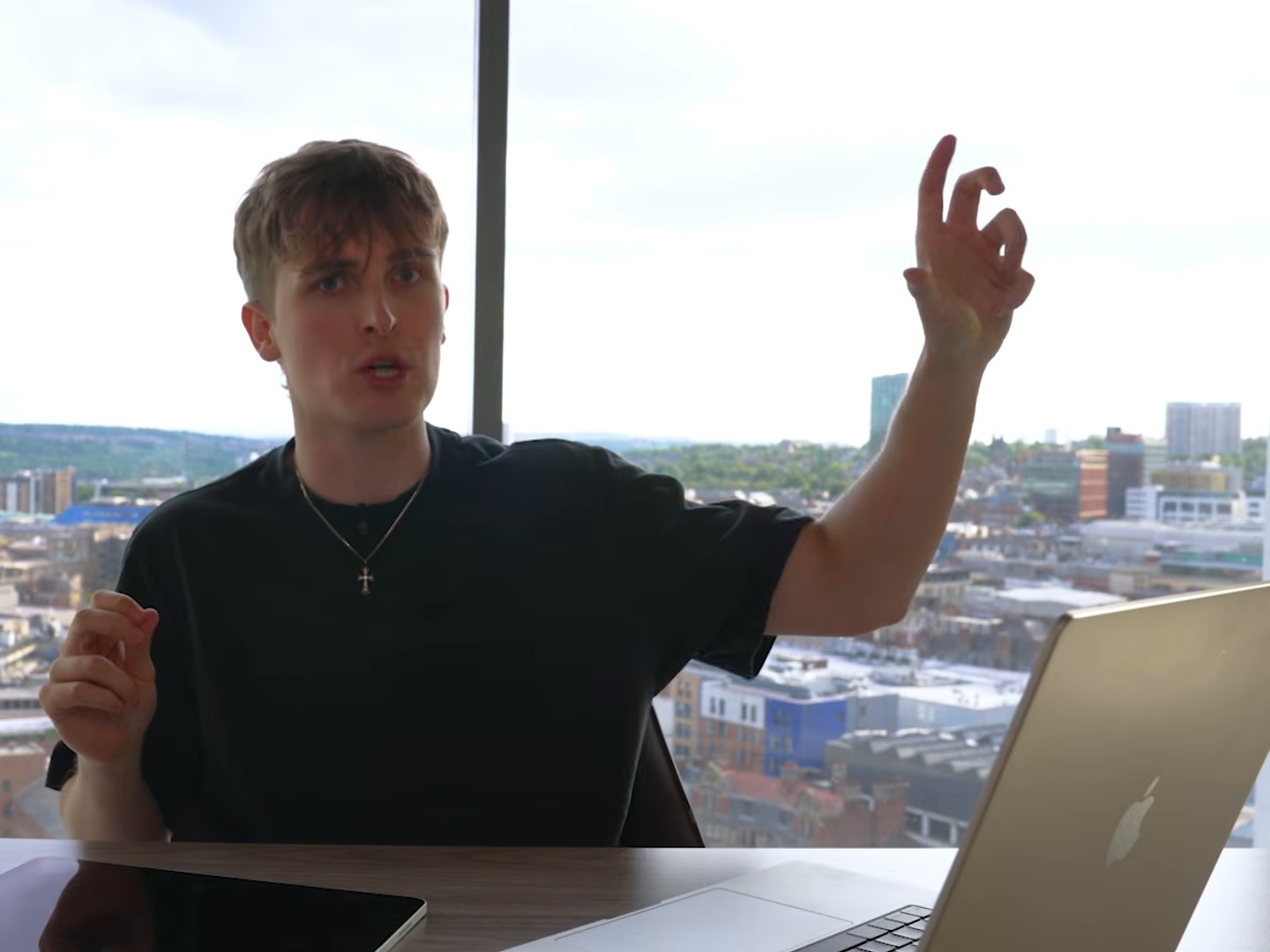 Jake Trinder at his desk above the Newcastle skyline, explaining with a raised hand